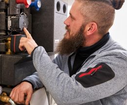 SHK-Fachhandwerker von WEME Heizung & Sanitär prüft eine Umwälzpumpe und Armaturen an einer Heizungsanlage, Wartungsarbeiten im Technikraum