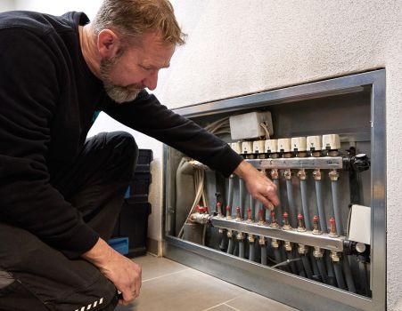 SHK-Fachhandwerker von WEME Heizung & Sanitär stellt einen Heizkreisverteiler ein, arbeitet an Ventilen und Rohrleitungen einer Heizungsanlage